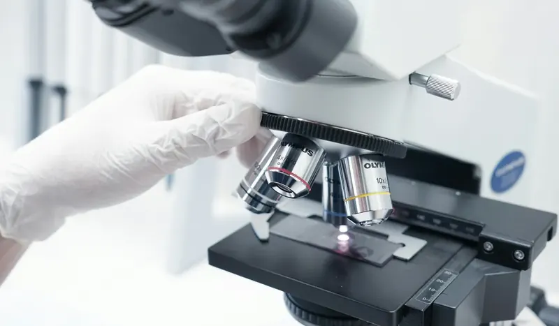 Microbiologist examining samples under a laboratory microscope